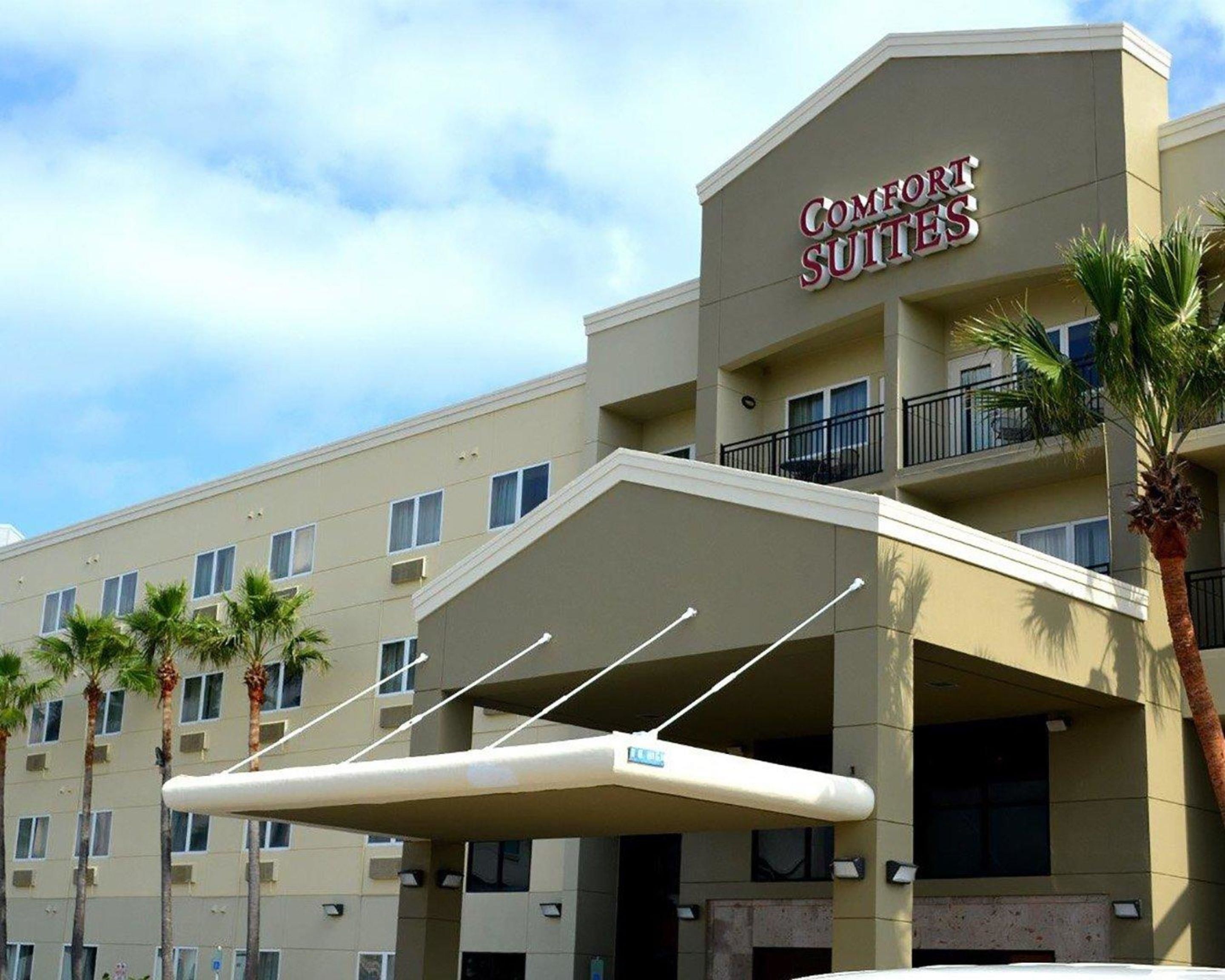 Un hotel chiamato Comfort Suites, dal design moderno, con un ingresso coperto e diversi balconi.