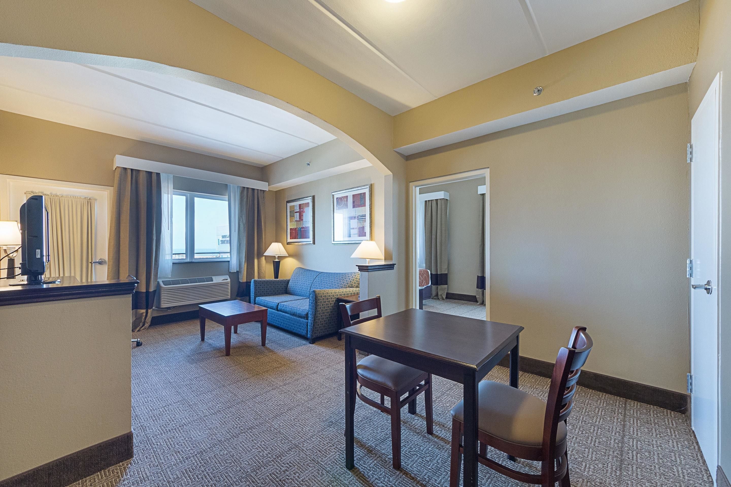 Una habitación de hotel con sala de estar, una mesa de comedor y un sofá.
