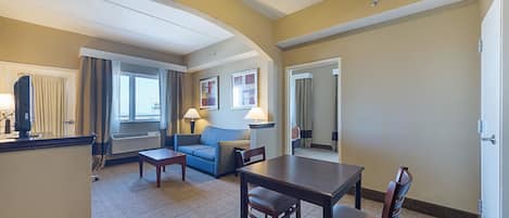 Una habitación de hotel con sala de estar, una mesa de comedor y un sofá.