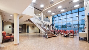 A spacious indoor area with a central staircase, large windows, and multiple seating areas. - Comfort Suites Beachside (South Padre Island)