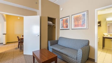 A compact living room with a sofa, a small table, and a dining area with chairs.