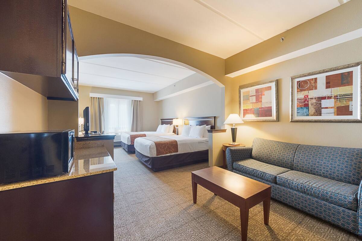 A hotel room with a bed, a sofa, a desk, and a TV.