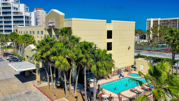 A hotel with a pool area, palm trees, and a sign reading "COMFORT SUITES".