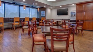 A dining area with wooden tables and chairs, a popcorn machine, and large windows. - Drury Inn & Suites Memphis Southaven (Horn Lake)
