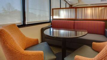 A seating area with a round table, cushioned chairs, and a bench with striped cushions.