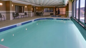 An indoor swimming pool with clear water, a tiled edge, and a seating area with chairs and a table. - Drury Inn & Suites Memphis Southaven (Horn Lake)