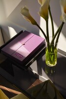 A purple box labeled "SPAUL HOTEL" on a table next to a glass vase with flowers.