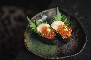 Une assiette de sushis, présentée sur une assiette foncée à la texture particulière.