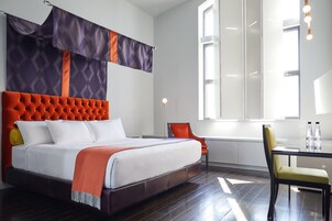 A modern hotel room with a large bed, a dining table, and a chair.