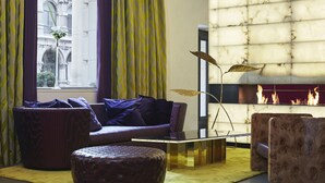 Una sala de estar moderna con un sofá, un reposapiés y una mesa de centro de vidrio.