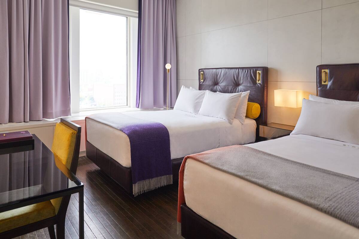 A hotel room with two beds, a desk, and a chair.
