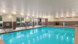 A swimming pool with a tiled deck, seating area, and a door leading to another room. - Fairfield Inn by Marriott Visalia Sequoia (Visalia)