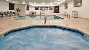 Una piscina con solárium de baldosas, un puesto de socorrista y sillas de descanso.