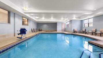 A swimming pool with a diving board, chairs, and a door.