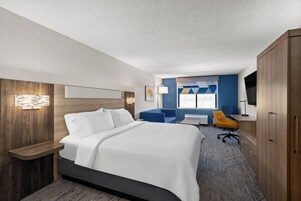 A hotel room with a bed, a desk, a chair, a TV, and a window.