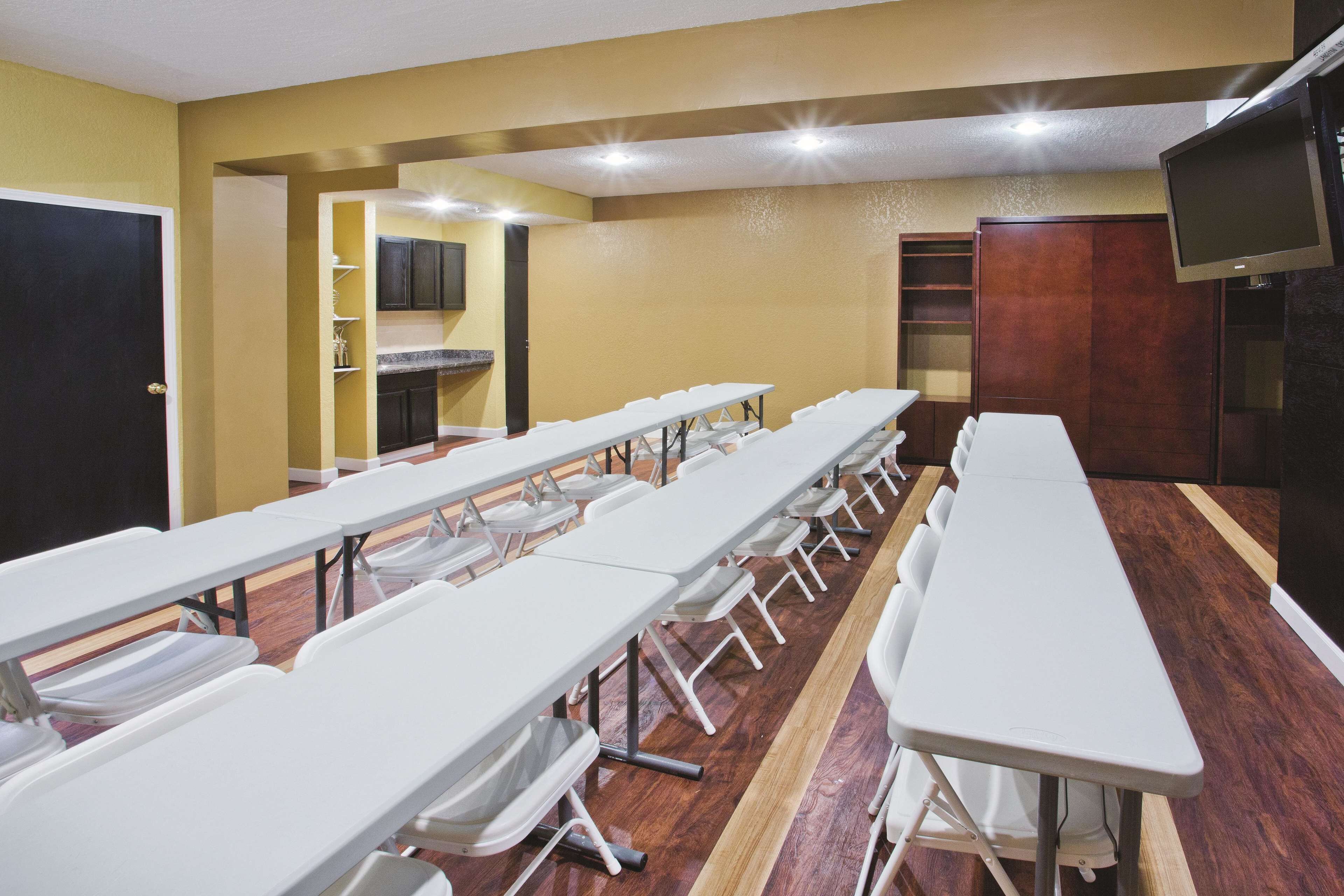 A conference room with long tables and chairs, a blackboard, and a television.