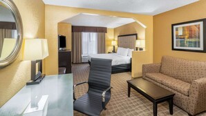 A hotel room with a bed, a desk, a chair, a sofa, and a mirror. - La Quinta Inn & Suites by Wyndham Hot Springs (Hot Springs)