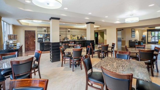 A spacious dining area with multiple tables and chairs, a kitchen in the background, and a modern chandelier. - La Quinta Inn & Suites by Wyndham Hot Springs (Hot Springs)