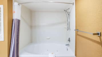 Una bañera blanca con cabezal de ducha, toallero y jabonera.