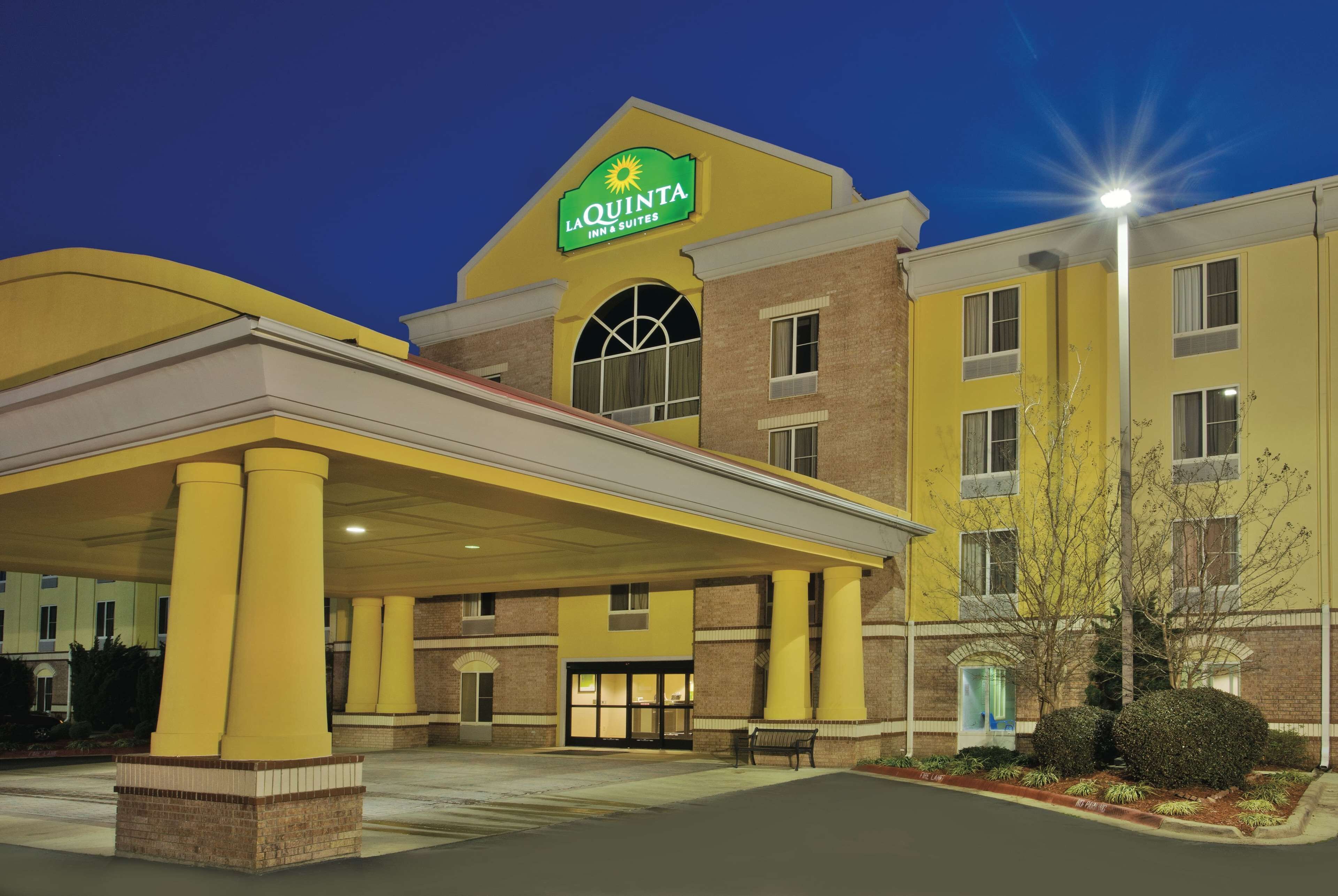 A La Quinta Inn & Suites building with a yellow facade, a covered entrance, and a sign above the entrance.