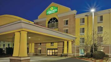A La Quinta Inn & Suites building with a yellow facade, a covered entrance, and a sign above the entrance.