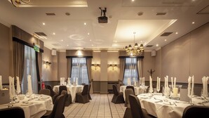 A hotel dining room with round tables set for service, ambient lighting, and a chandelier. - Holiday Inn Glasgow City Theatreland by IHG (Glasgow)