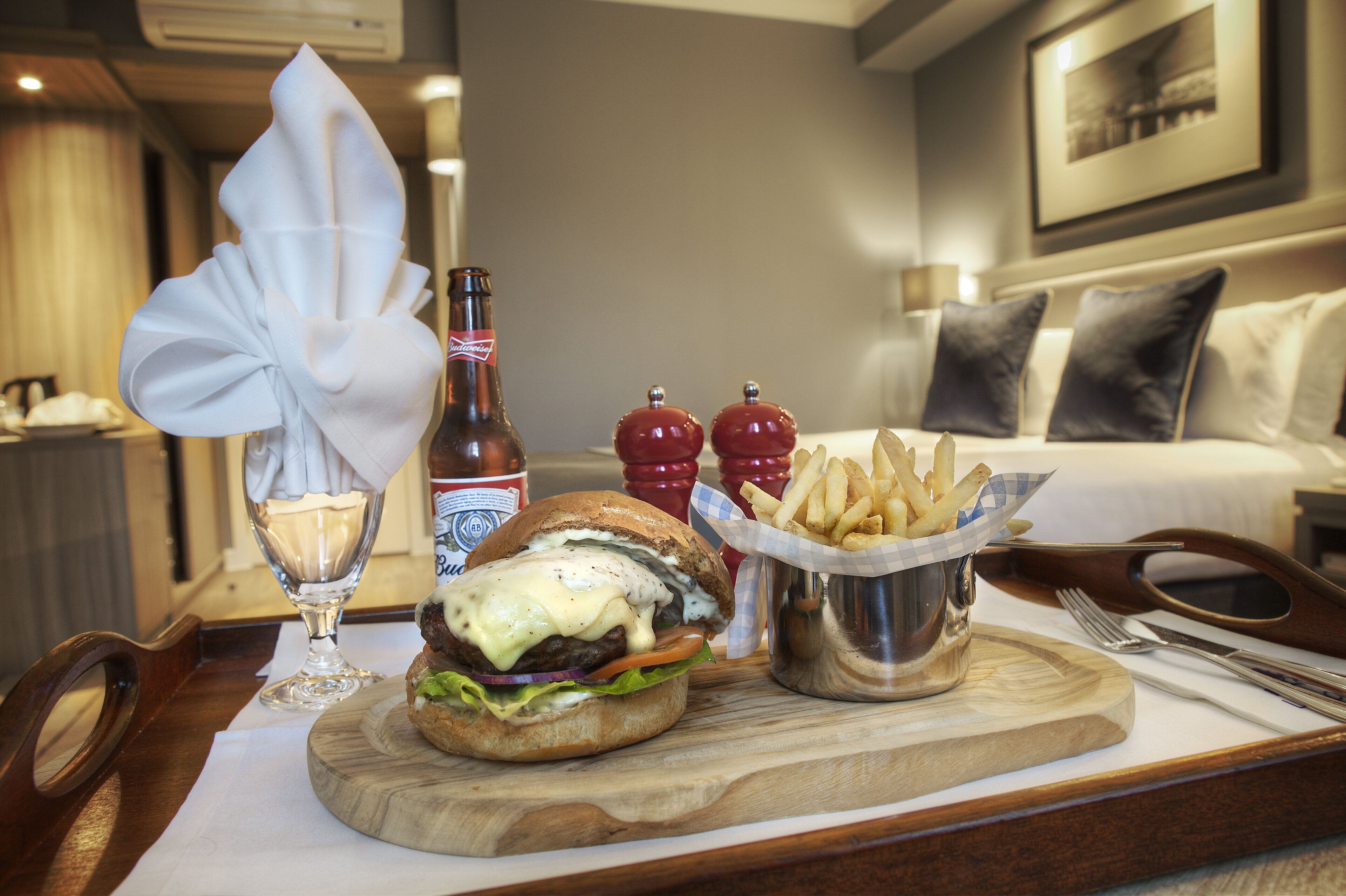 A dining table with a burger, fries, a bottle, and condiments.