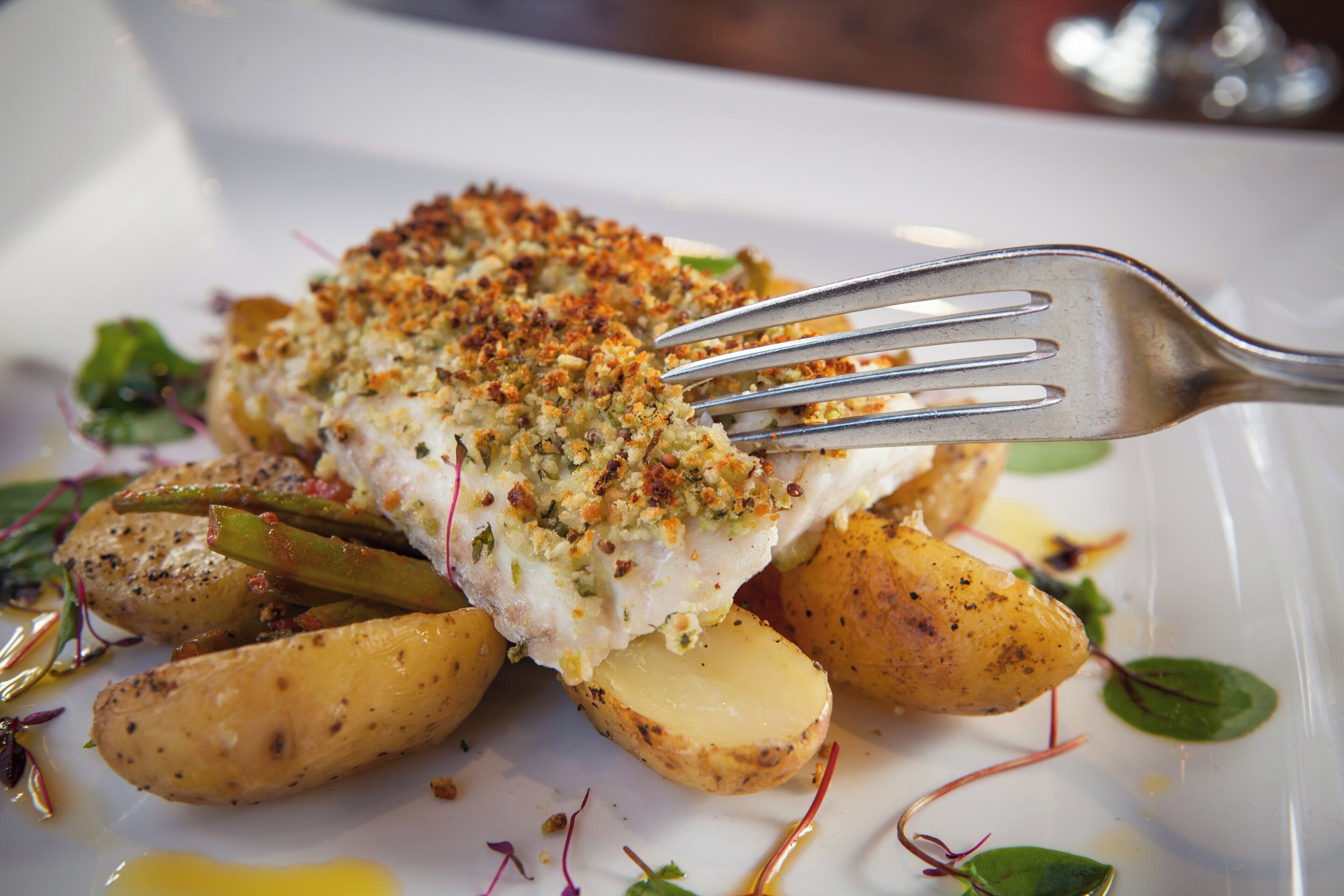 A plated dish with fish, potatoes, and greens.