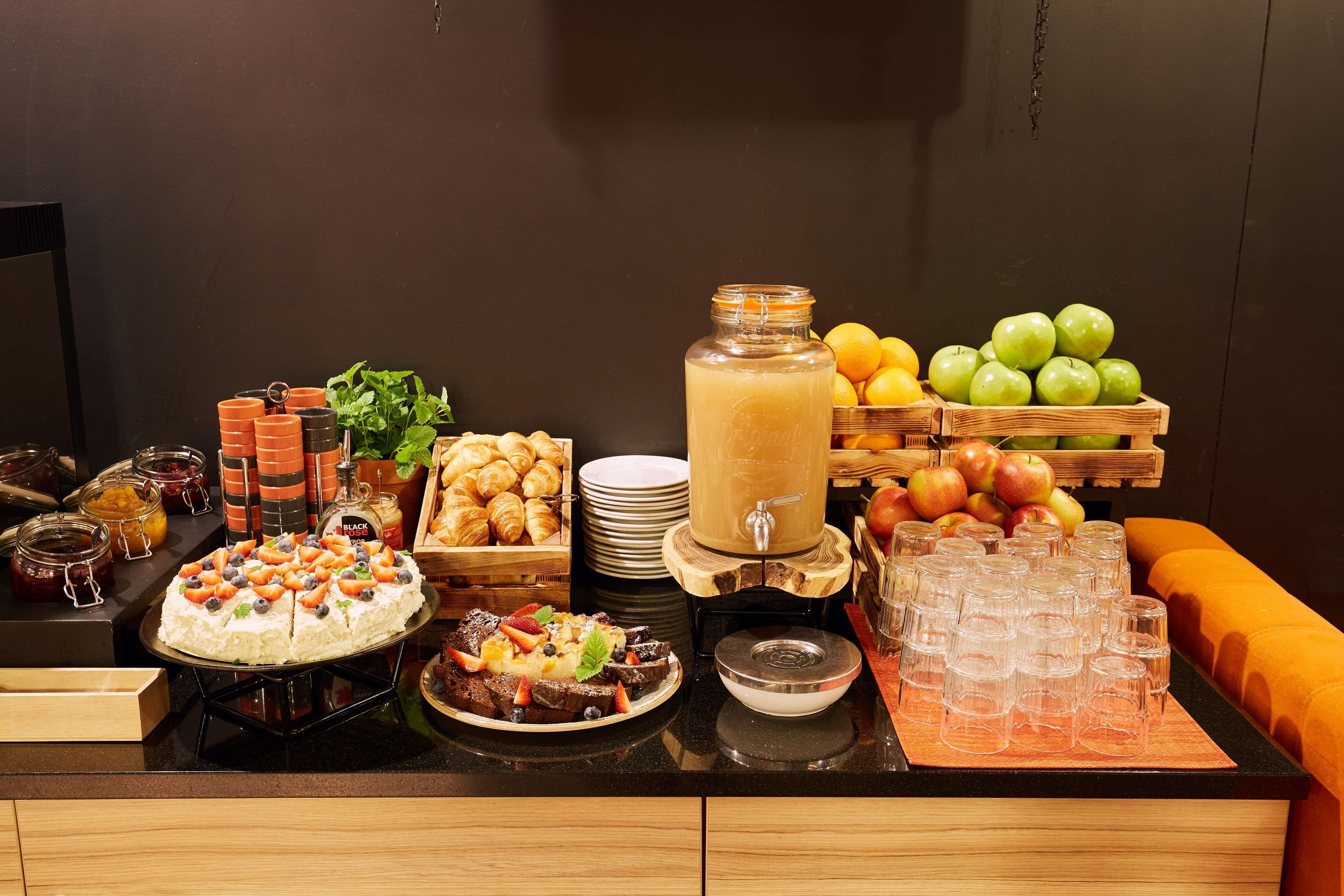 A buffet with various food items, including a cake, fruits, and a beverage dispenser.
