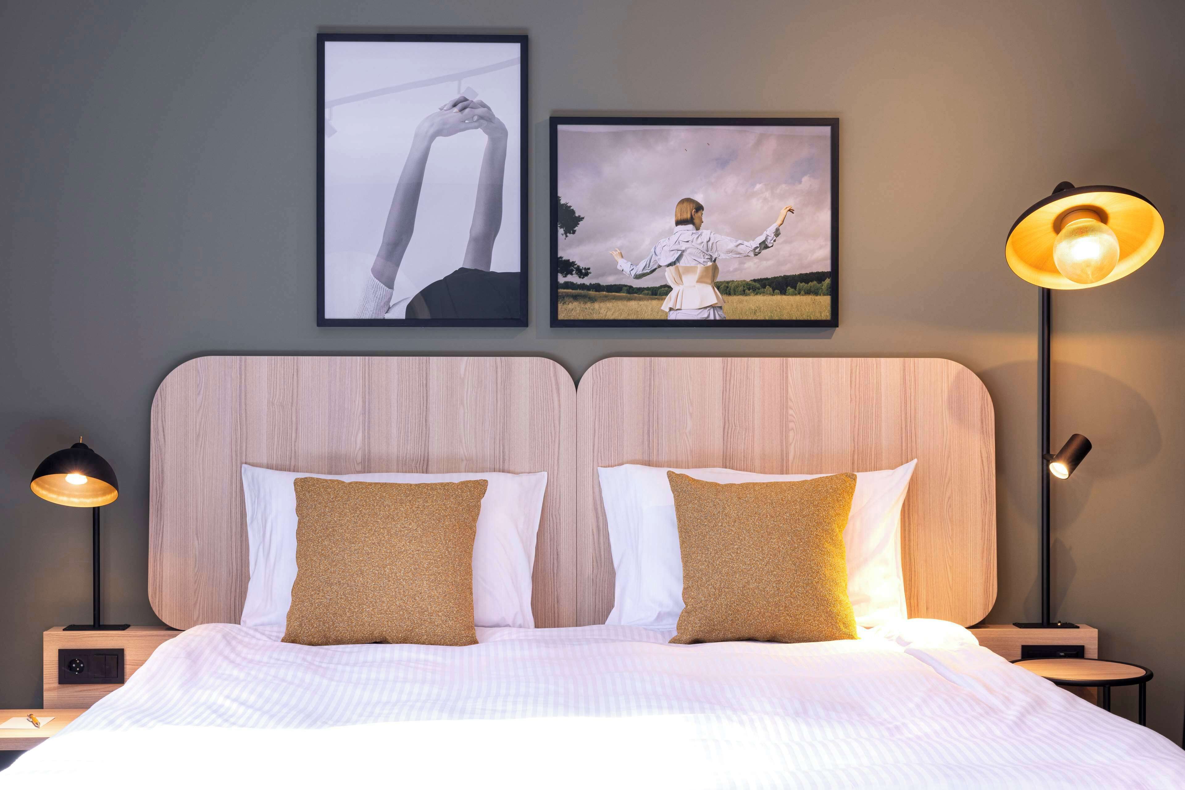 A neatly made bed with two pillows, a wooden headboard, and two bedside lamps.