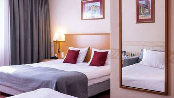 Une chambre d’hôtel avec deux lits, une table de chevet avec une lampe et deux tableaux encadrés au mur.