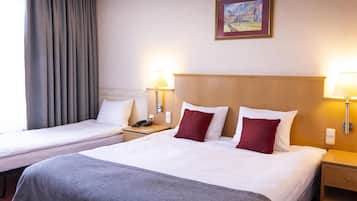 Ett hotellrum med två sängar, en tavla på väggen och sänglampor.