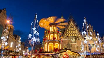 Un edificio histórico con una torre de reloj y arquitectura ornamentada, rodeado de luces y decoraciones festivas.