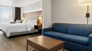 Ein Hotelzimmer mit Bett, Sofa, Couchtisch und Lampe.