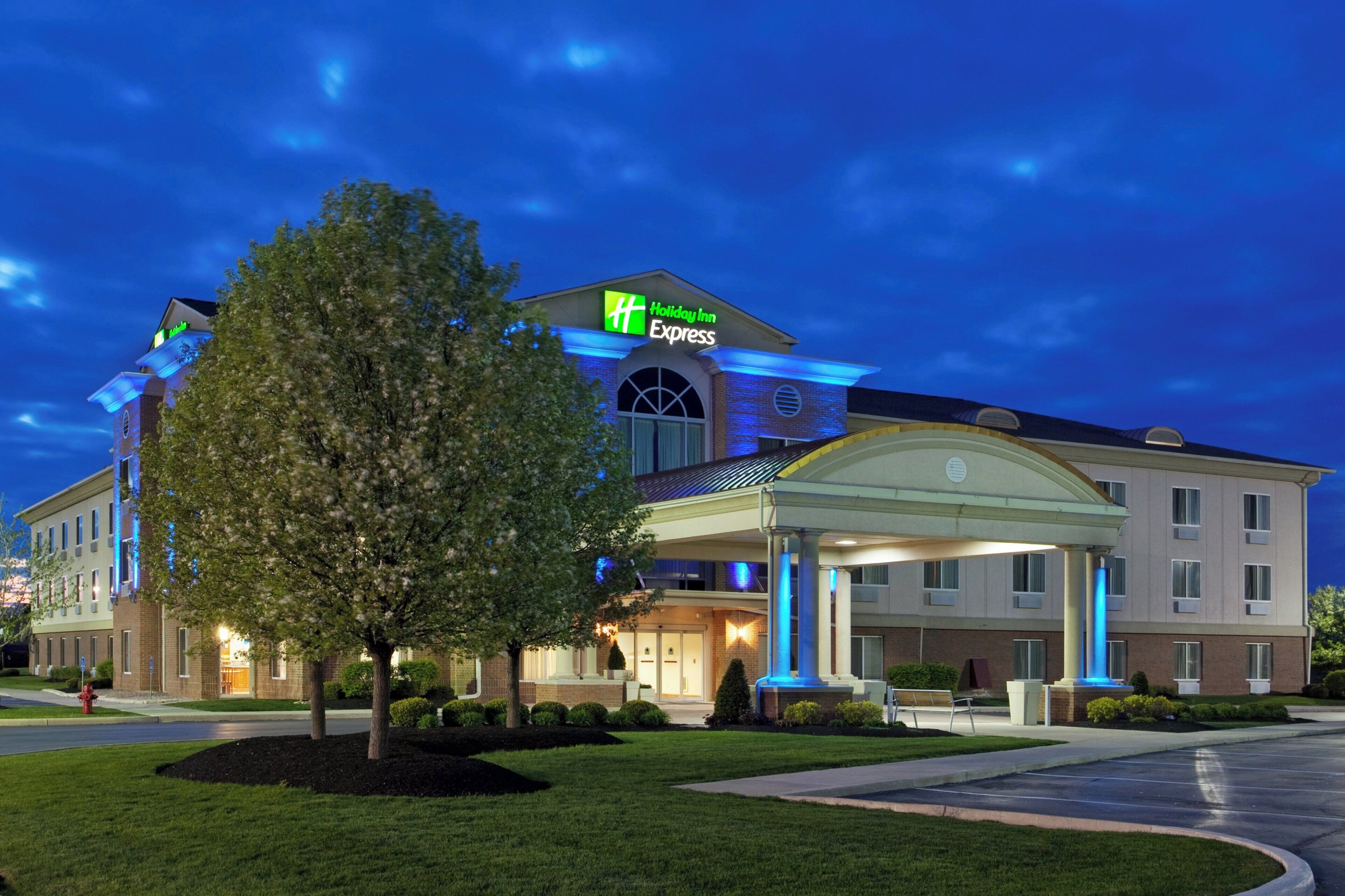 A Holiday Inn Express hotel with a covered entrance, a large tree in front, and a well-maintained lawn.
