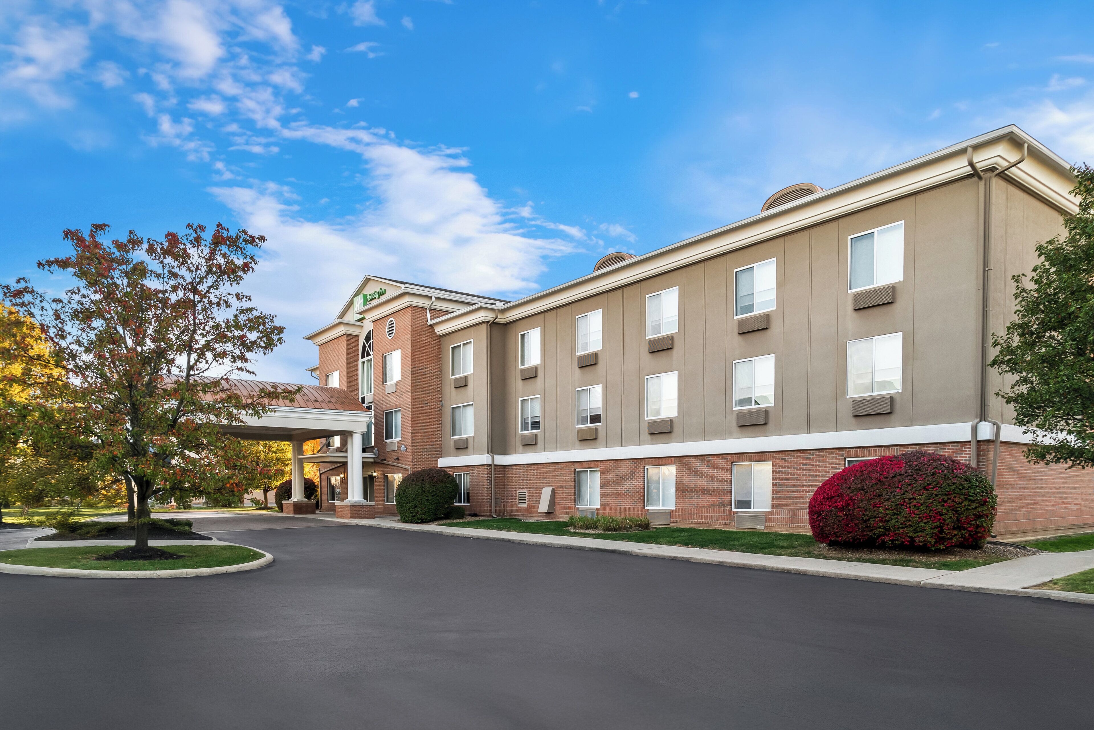 A multi-story hotel with a brick facade, large windows, and a covered entrance.