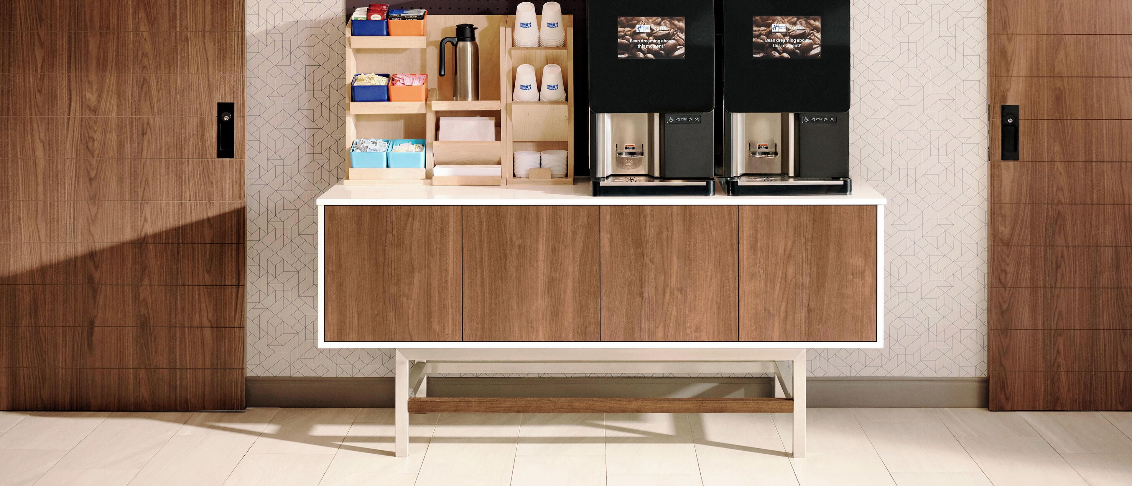A modern kitchen with a wooden cabinet, a coffee machine, and storage shelves.