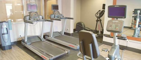 Une salle de sport équipée de tapis de course, d’un vélo elliptique et d’un vélo d’appartement.