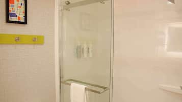 A glass-enclosed shower with a towel rack, a toilet, and a shelf with toiletries.