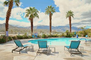 A pool area with lounge chairs, palm trees, and a mountainous backdrop. - Hampton Inn & Suites Cathedral City (Cathedral City)