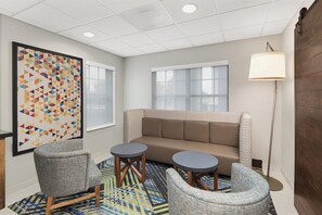 A modern room with a sofa, two armchairs, a patterned rug, and a large geometric artwork on the wall. - Holiday Inn Express & Suites Byron by IHG (Byron)