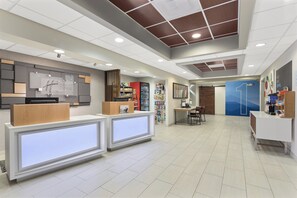 A hotel reception area with a modern design, including a reception desk, a seating area, and a wall with various amenities. - Holiday Inn Express & Suites Byron by IHG (Byron)