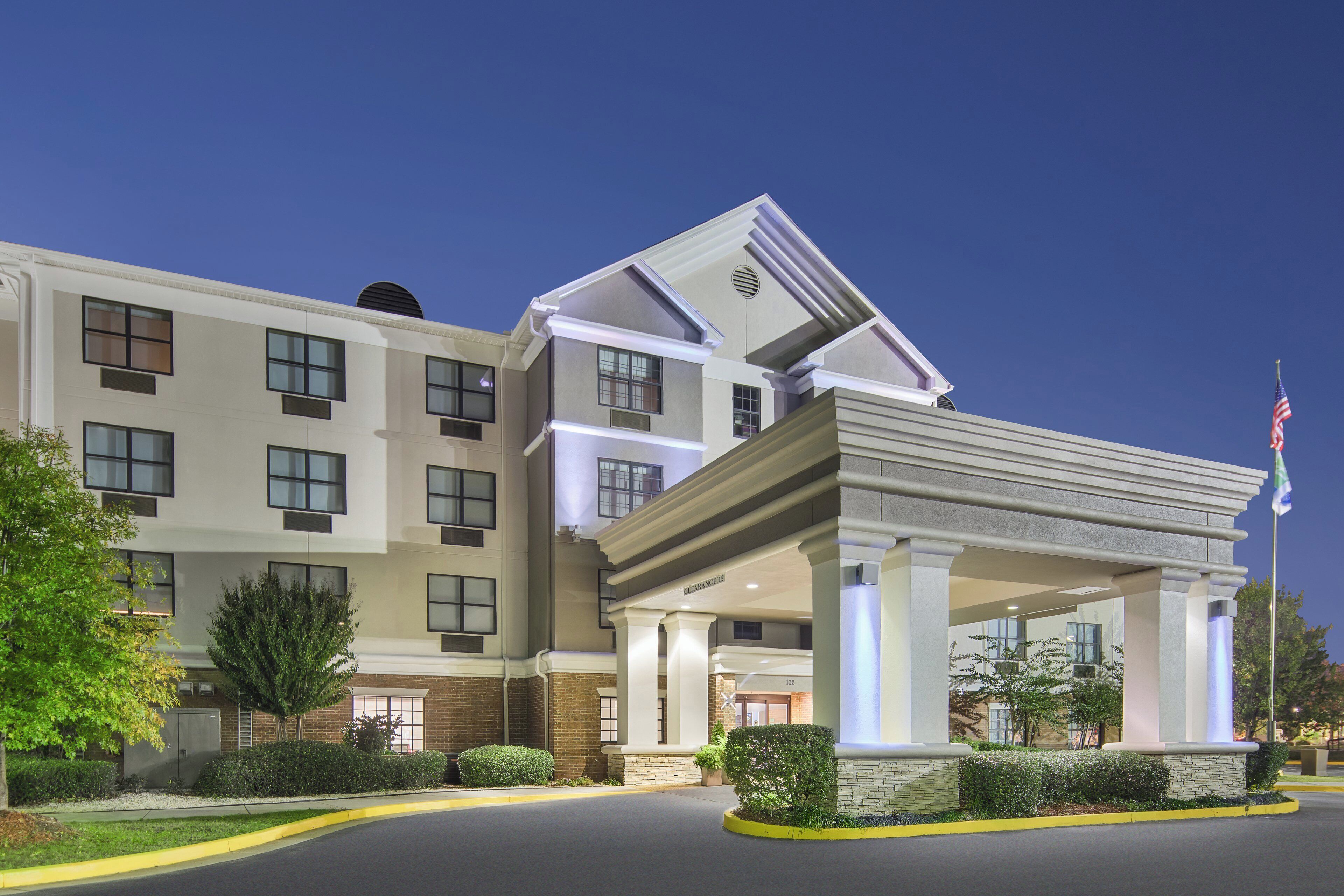 A multi-story hotel with a covered entrance and a flagpole.