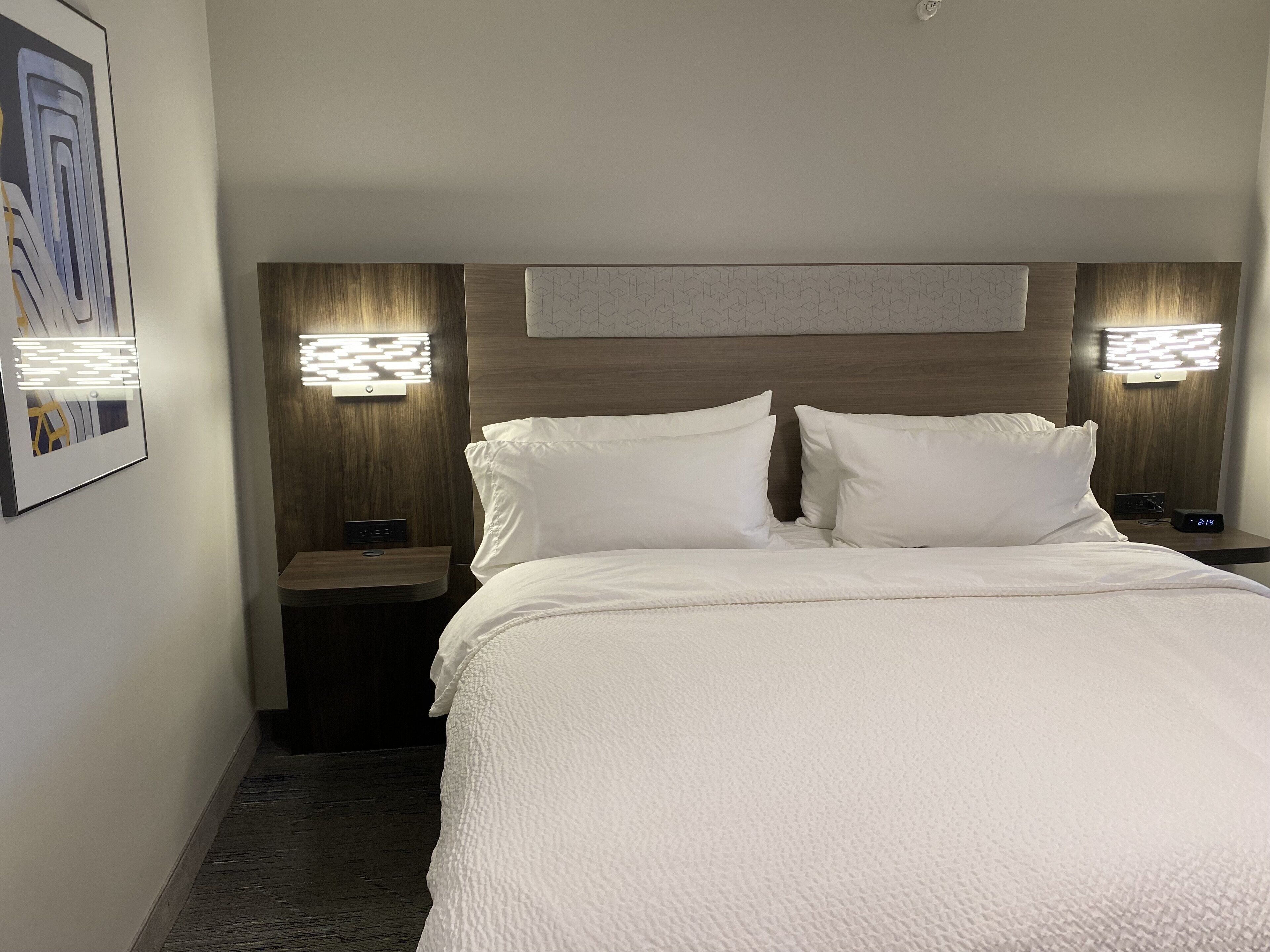 Ett hotellrum med en stor säng, två sängbord och väggmonterad belysning.