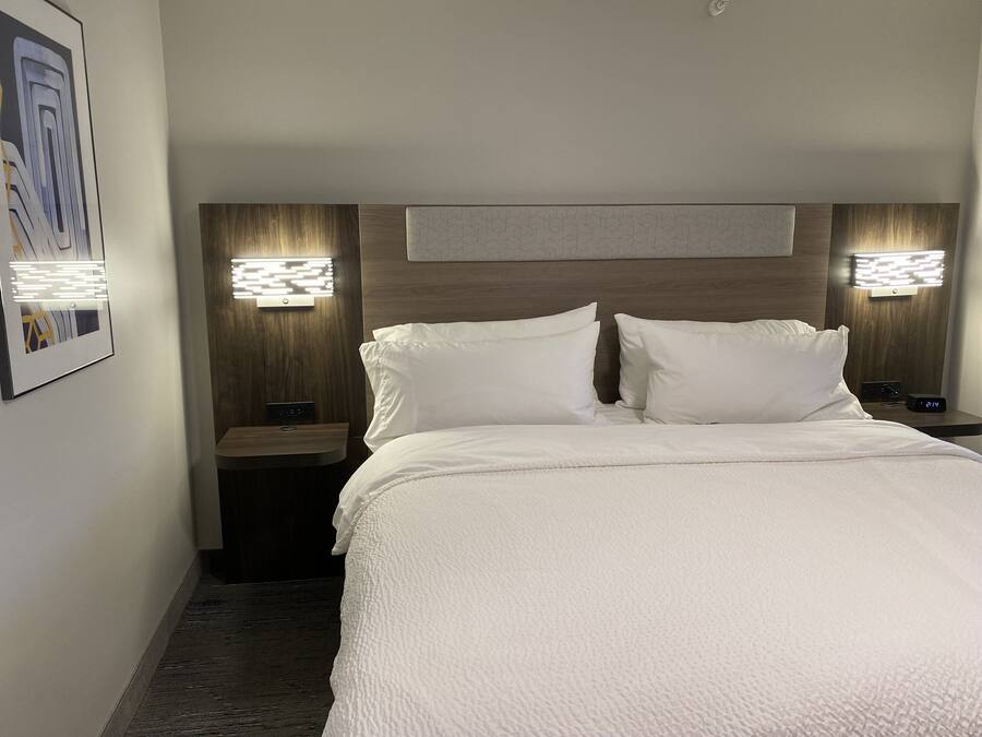 Ett hotellrum med en stor säng, två sängbord och väggmonterad belysning.