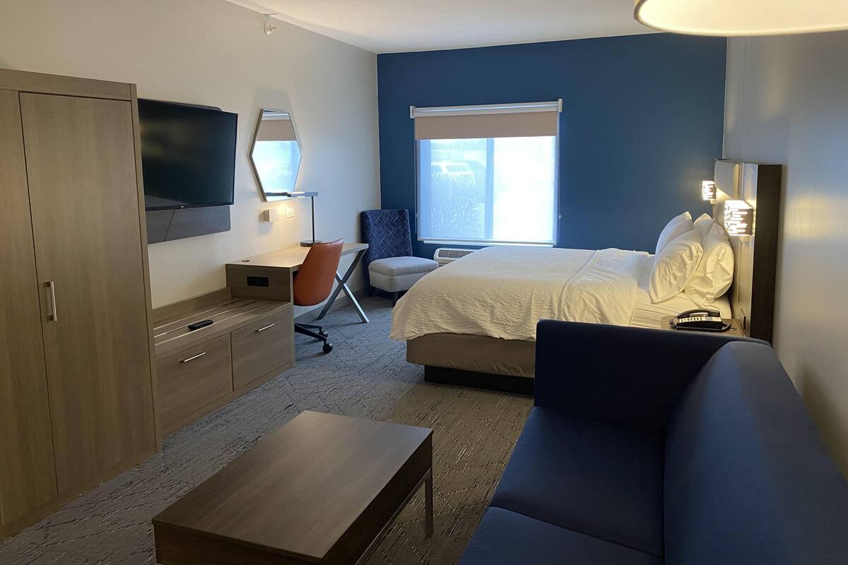 Une chambre d’hôtel moderne équipée d’un lit, d’un bureau, d’une chaise, d’une télévision et d’une fenêtre.
