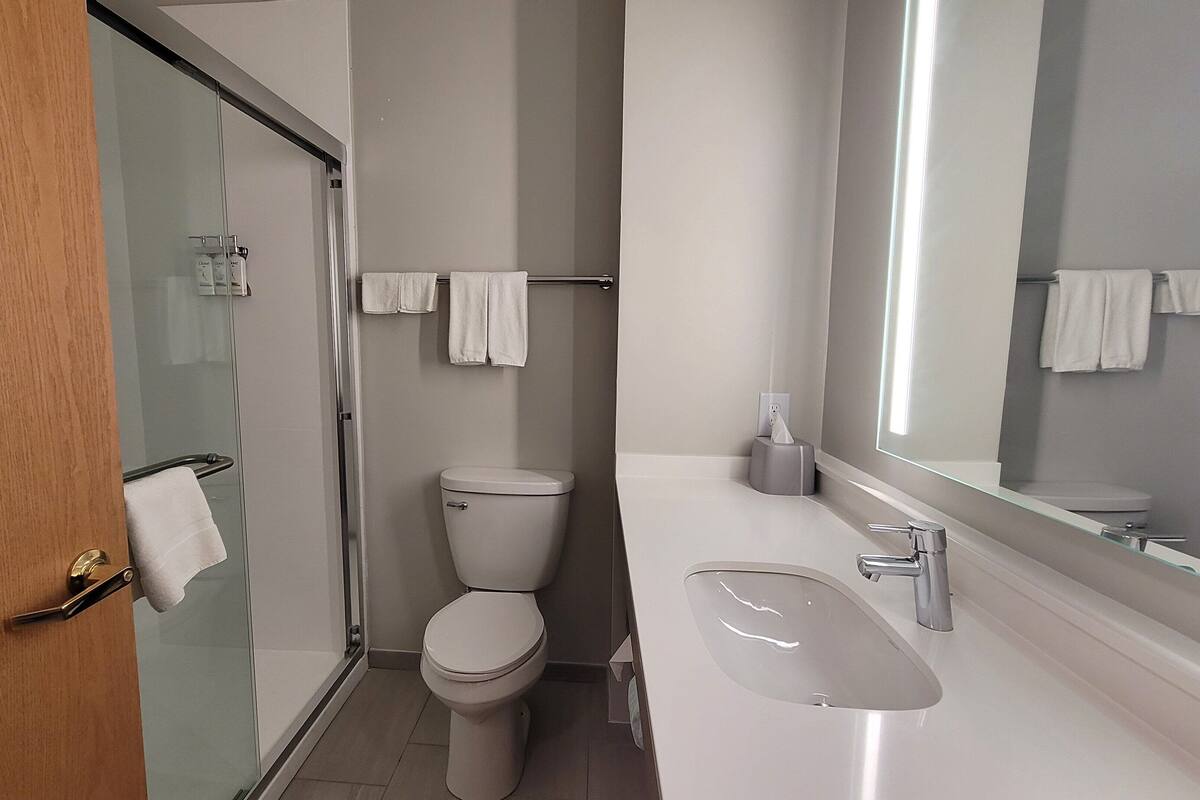 Une salle de bain moderne avec une douche à parois de verre, des toilettes, un lavabo et un grand miroir.