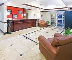 Un vestíbulo con mostrador de recepción, recepcionista, estatua, sofá de cuero y puerta de cristal que da al exterior.