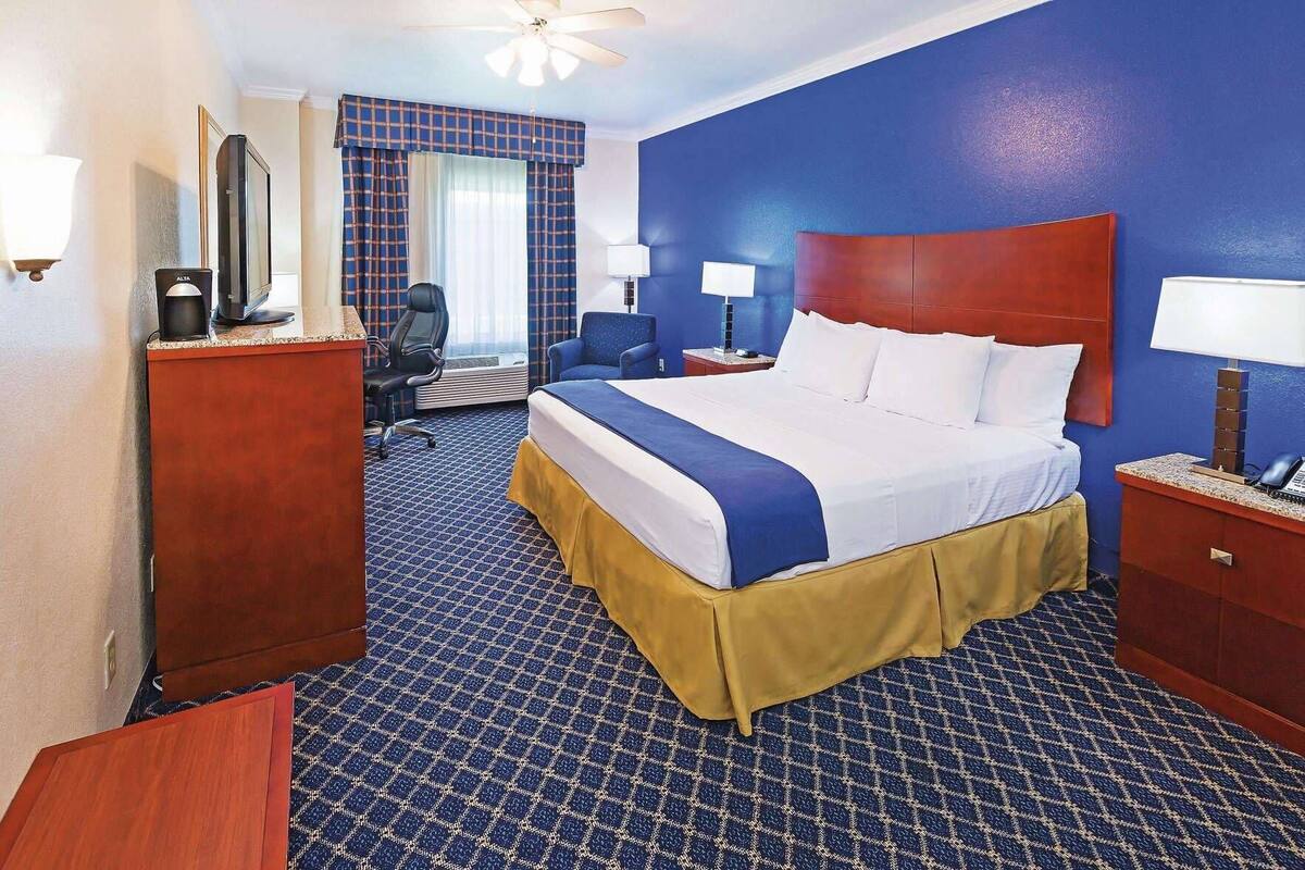 A hotel room with a bed, desk, chair, and a television.