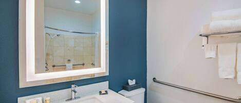 Un baño con lavamanos blanco, un espejo, toallero y retrete.